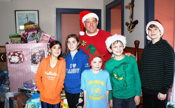 Maisano stands with his son and other child volunteers in front of the toy pile at the 2012 drive. 