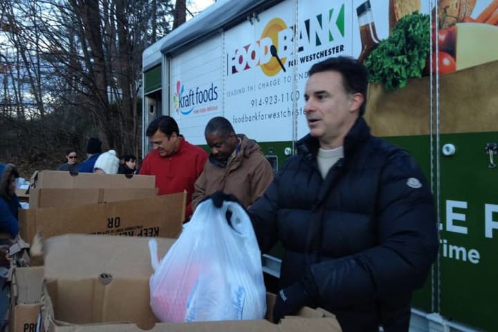 Food Bank for Westchester board members Charles Day, Willard Hill Jr., and Scott Boilen hand out food during a turkey distribution event for the Mount Kisco Interfaith Food Pantry.