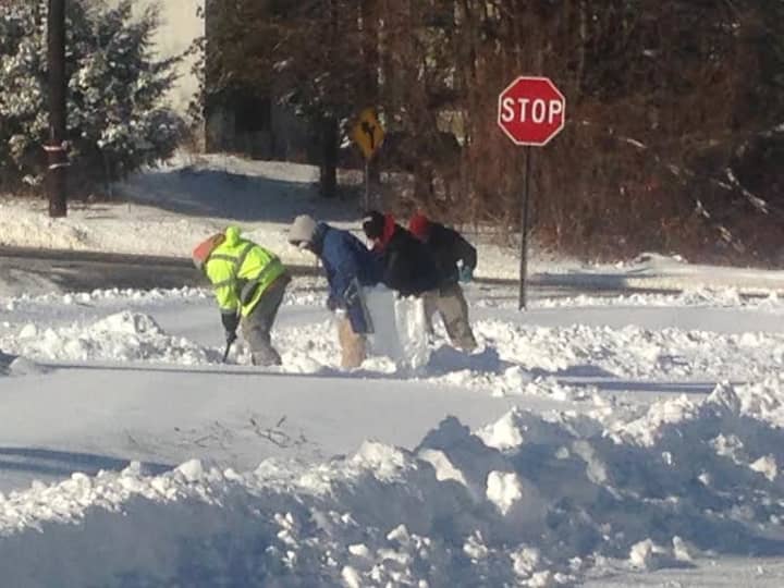 A crew of workers bundles up from head to toe to clear the snow from a Ridgefield sidewalk. 