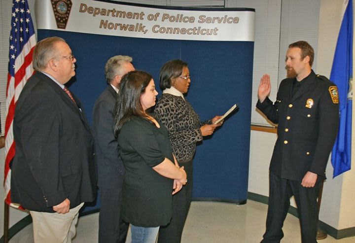 Sgt Markert is administered the oath of office by Commissioner Collier-Clemmons, in the presence of his wife, while Mayor Rilling and Commissioner Yost look on.