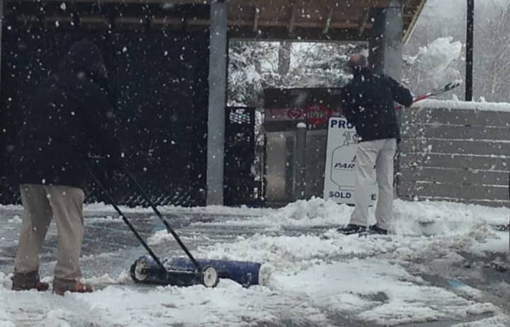 Mobil gas station employees shovel snow Monday afternoon. 
