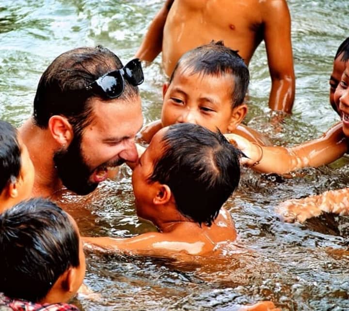 Harry Devert playing with local children on a previous trip to Laos.