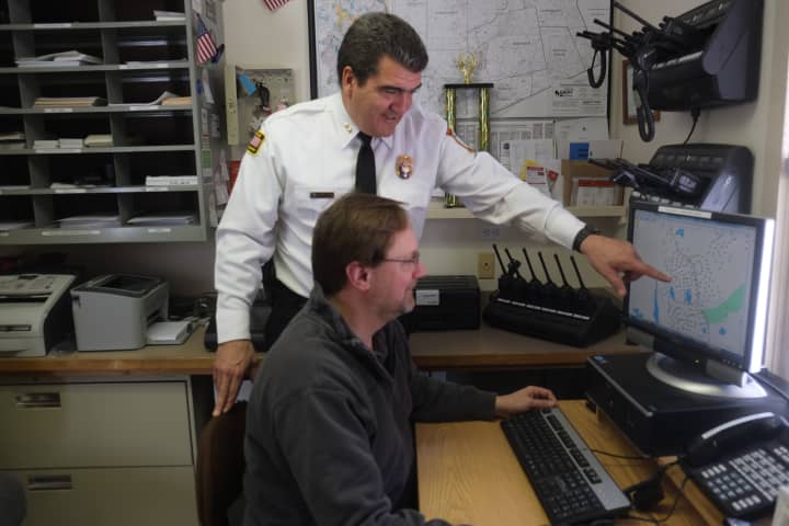 Pound Ridge Police Chief David Ryan (standing) and Todd Baremore monitor power outages using new software. 