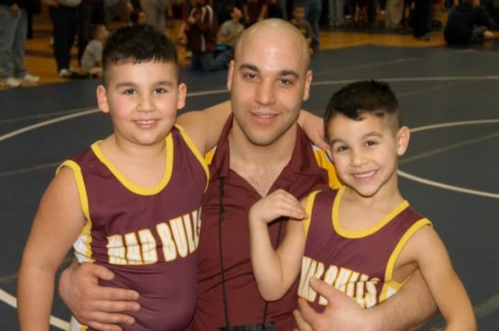Nick Singer, right, and his brother, Jason Jr., pose with their dad, Jason Sr., after both won state championships for the Norwalk Mad Bulls youth wrestling team.