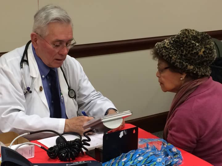 John Gibb, RN, performs a blood pressure screening and record of the numbers to a visitor.