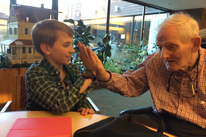 Henry Benton, left, the youngest volunteer at the Waveny LifeCare Network in New Canaan, shares a high-five with Harvey Chandler.