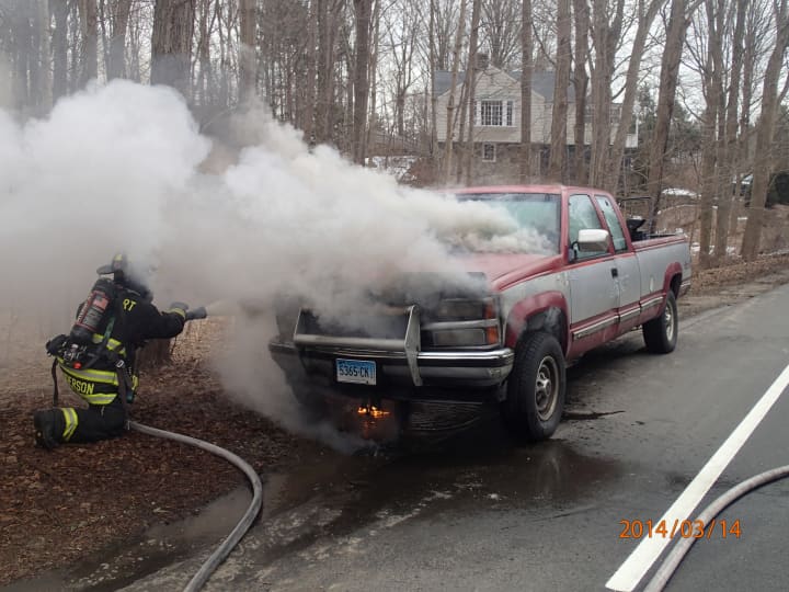 A Westport firefighter works to extinguish a pickup truck fire on Weston Road Friday morning.