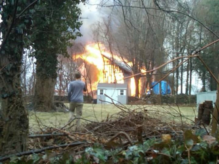 A two-story barn behind a home on Fox Run Road in Norwalk is damaged in a fire Saturday. 