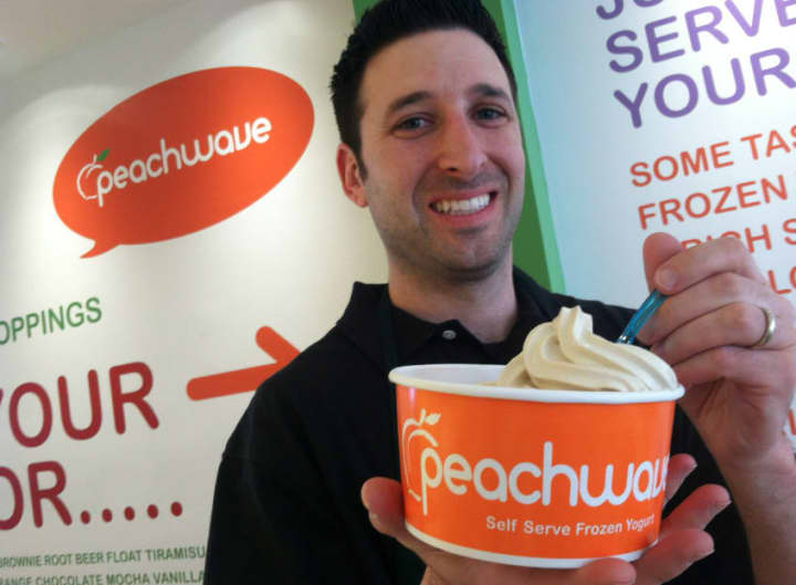 Manager Ryan Ventura holds up a frozen yogurt at Peachwave, a new frozen yogurt business in New Canaan. It is located at 11 Forest St.
