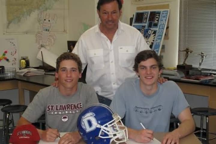 Darien football players Daly Hebert, left, and Silas Wyper, right, announced their college plans with coach Rob Trifone.