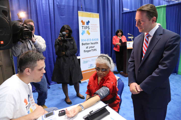 Westchester County Executive Robert P. Astorino watches as volunteer technician João Pinto, a student at Pace University, takes the vital signs of Shirley Hunter, a resident of the Soundview Apartments at United Hebrew in New Rochelle.