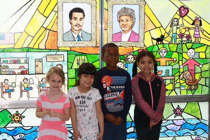 Several of the Lee F. Jackson first-grade artists who created the stained-glass work stand in front of the exhibit.