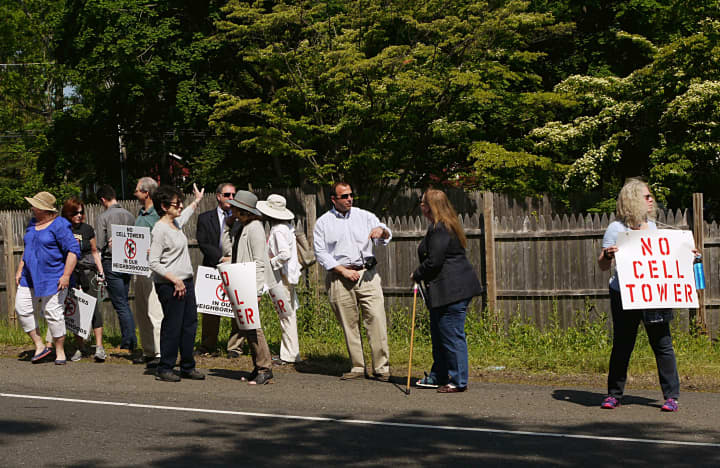 Dozens of people gather at the side of Greens Farms Road in Westport on Tuesday to fight a proposed cellphone tower. 