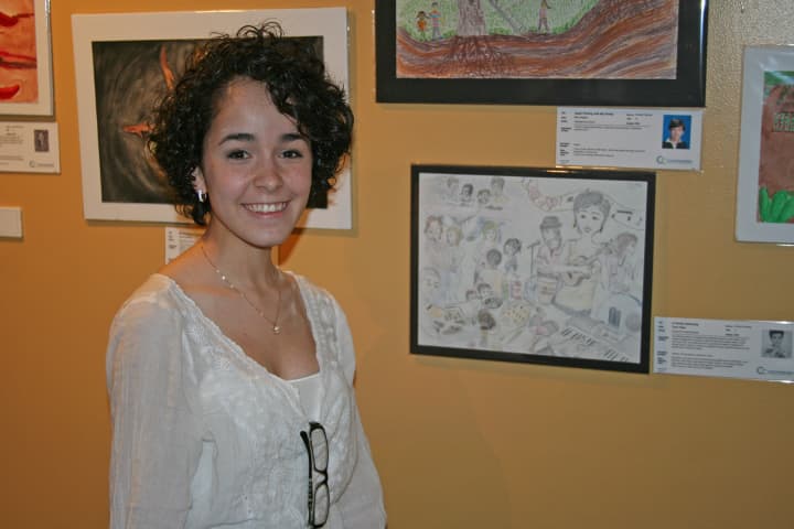 Taina Pagan, 17, a student at The Center for Global Studies in Norwalk, stands by her entry, A Family Gathering, at the reception for the 18th International Childrens Art Show.