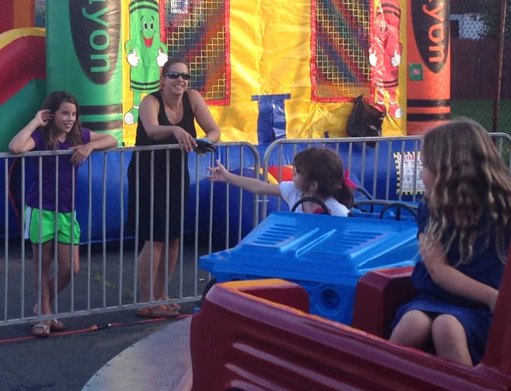 Jackie Mannix reaches out for her mom, Fran, as she goes round-and-round on a ride, along with Sofia Butini (right) at St. Vito&#x27;s Festa Thursday. 