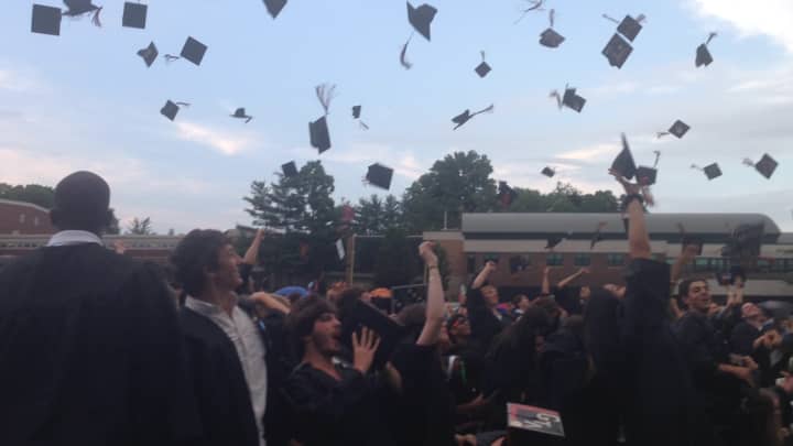 Seniors toss their caps after receiving their diplomas Wednesday on the Mamaroneck High School baseball field. 