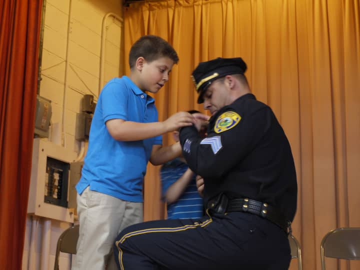 New Fairfield Police Sgt. Edward Nook has his two sons, 5-year-old Zackery and 9-year-old Edward, help him pin his new badge to his uniform. 