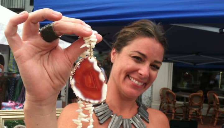 Meredith Bagley of Norwalk holds up one of her creations, a coral with an agate pendant necklace at New Canaan&#x27;s annual Village Fair and Sidewalk Sale on Saturday.