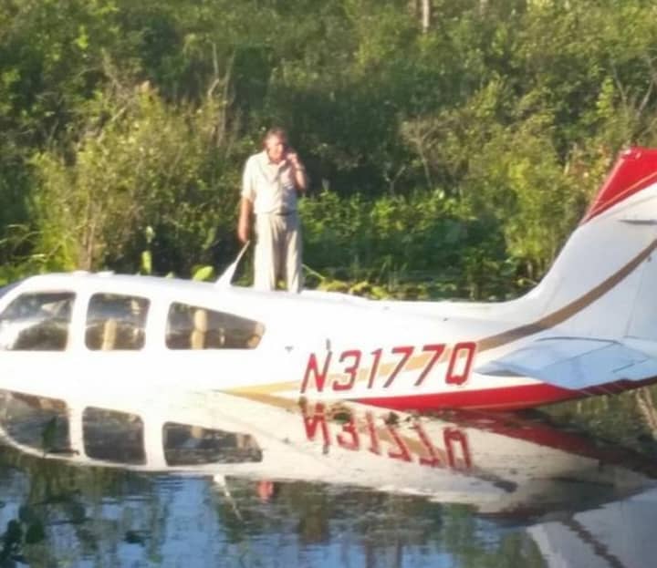 The pilot is waiting on top of his plane awaiting rescue after he landed in a pond near the Danbury Airport. 
