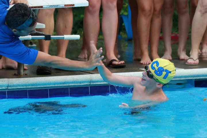Chappaqua Swim &amp; Tennis Club swimmer Sam Mason is greeted after finishing a race in the !0-Under boys division.