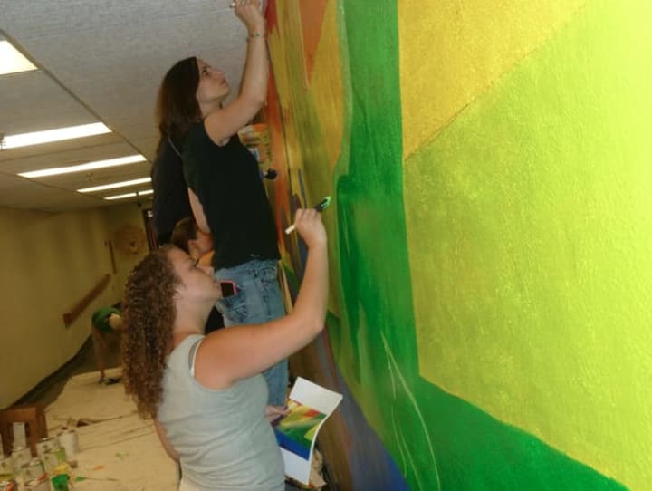 Jacki Loomis, 26, from Meriden, bottom and Heather Ferreira, 36, top from New Haven New Haven, are both art directors with Wilton-based Epsilon and worked on a mural at Trailblazers Academy Charter School  on Lockwood Avenue in Stamford.