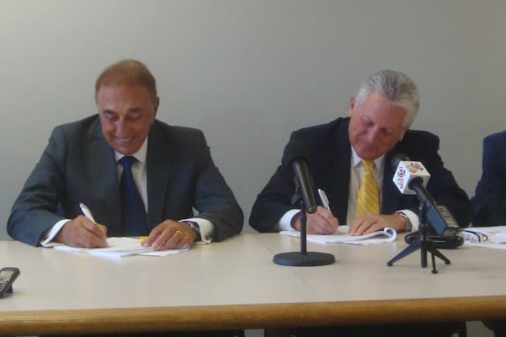 Michael DiScala and Norwalk Mayor Harry Rilling sign agreements to develop the property on Smith Street Thursday.