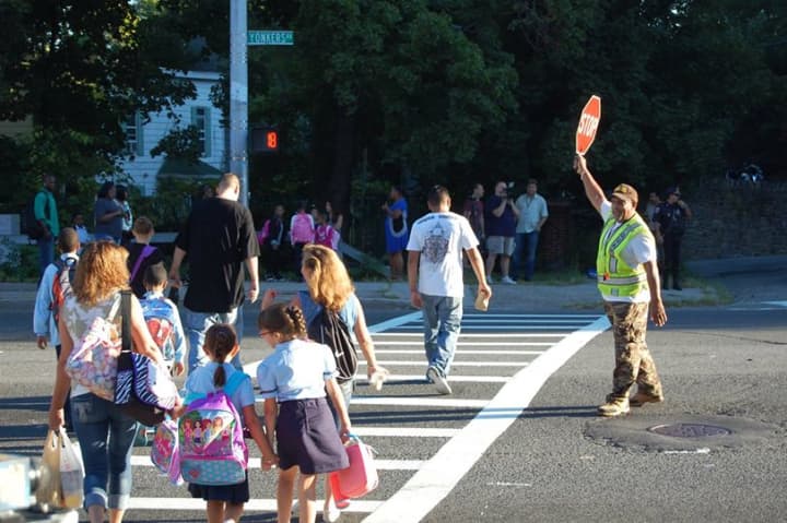 Children walk across the street as a Yonkers crossing guard watches the traffic. 