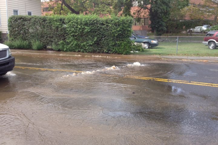 Water spills onto the street following a main break in South Norwalk Wednesday.
