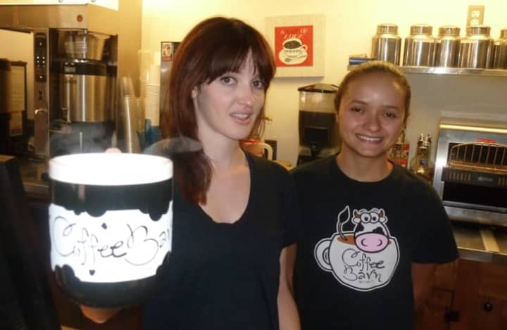 Kayla McArdle, left, co-owner of Wilton&#x27;s Coffee Barn holds a steaming cup of coffee on National Coffee Day Monday. Also pictured is employee Natalia Martins, 22, of Bridgeport.