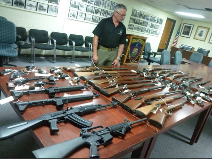 Stamford Police Sgt. Tom Wolff looks over the handguns, rifles and automatic rifles turned in to police as part of the gun buyback program.