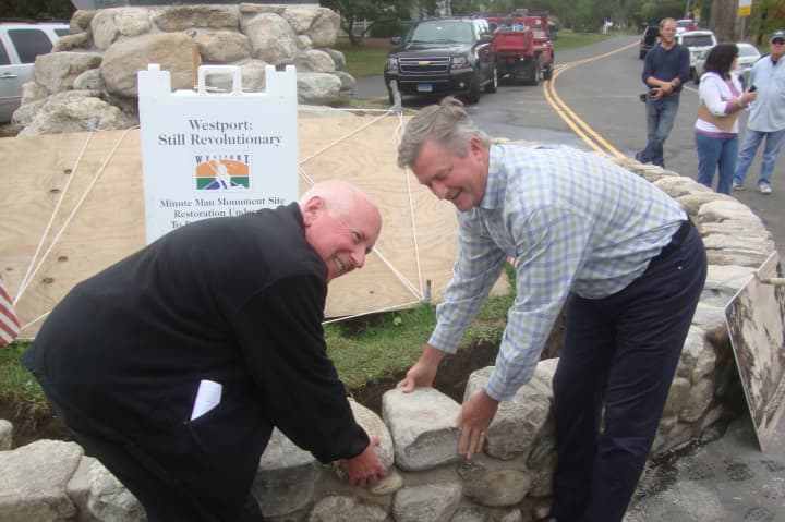 Westport First Selectman Jim Marpe and Sam Gault of Gault Energy and Stone lay the capstones of the fieldstone wall around the Minute Man Monument.
