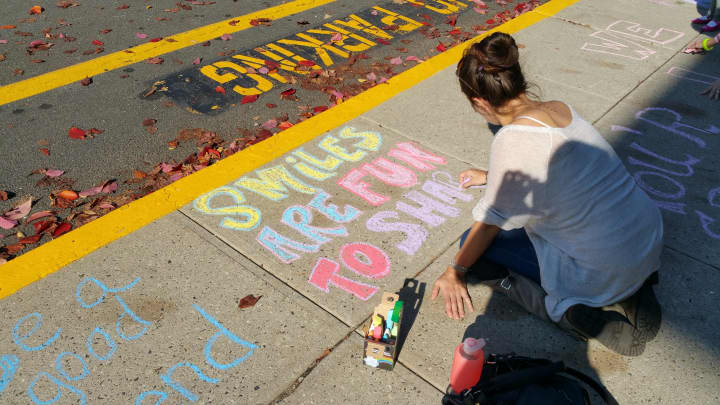 Parent Brieana Kennedy draws &quot;smiles are fun to share,&quot; at Kings Highway Elementary School on Friday, Oct. 17, as a part of the Kindness in Chalk movement.