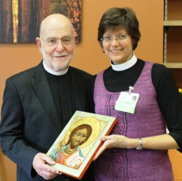 Pastor Carol Fryer presents a hand-painted icon of Christ to the Reverend Peter Bannan.