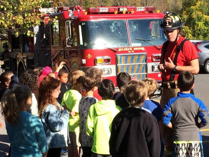 A member of the Goldens Bridge Fire Department explains fire safety to children. 