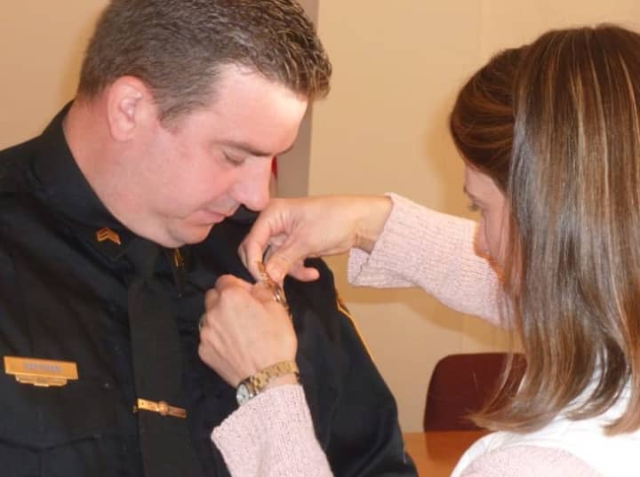 Lisa Hartman pins the sergeant&#x27;s badge on to her husband David Hartman, who was officially promoted to sergeant in a ceremony Monday at the Wilton Town Hall Annex.