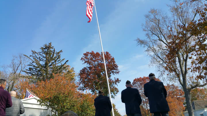 Three veterans stand in salute as a bugle player performs Taps.