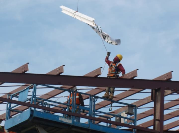 Construction worker Alejandro Aguilar grabs the ceremonial beam with a Convent of the Sacred Heart flag attached to it during the &quot;topping off&quot; ceremony Thursday for the school&#x27;s new athletic center.