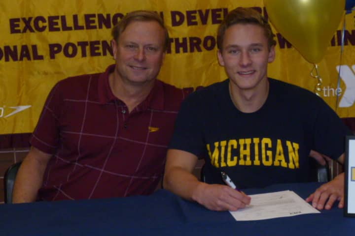 Wilton High School senior signs his letter of intent to attend Michigan. He is joined by Randy Erlenbach, the director of competitive aquatics for the Wilton Wahoos.