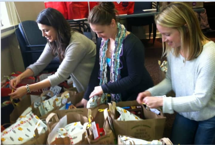 Family Centers staffers Jenna DiPaola, left, and Kara O&#x27;Connor, center, are joined Monday by volunteer Jamie Overman of Bedford, N.Y., right, in preparing Thanksgiving baskets for needy families served by the organization.