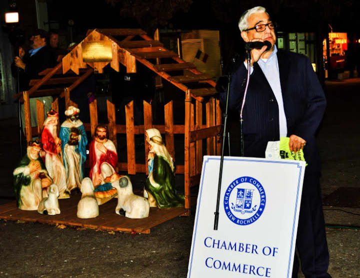 New Rochelle Chamber of Commerce Director Bob Marrone flanked by a manger scene.