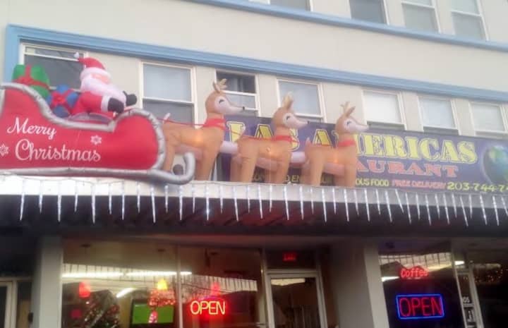 An inflatable Santa and reindeer are flying across the sign at the Las Americas restaurant on Main Street in Danbury. 