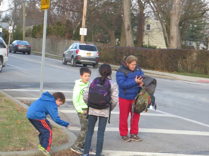 An adult waits for three children from Osborn Elementary School on Thursday and then crosses Boston Post Road to Sonn Drive.