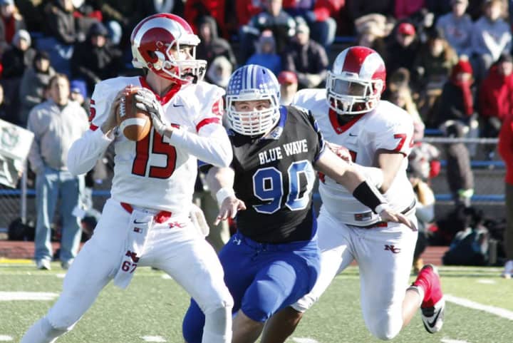 New Canaan quarterback Michael Collins looks for a receiver under pressure from Darien&#x27;s Mark Evanchick.