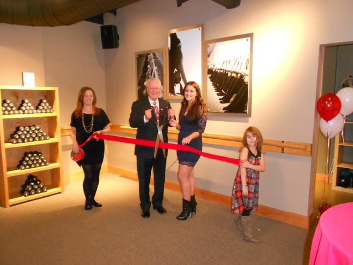First Selectman Michael Tetreau (center) is helped by owner Laura Laboissonniere (right) in the ceremonial ribbon cutting that took place inside the Pure Barre Studio, Friday, Dec. 5.