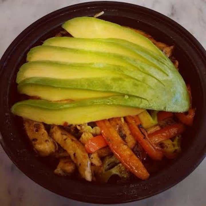 Chicken quinoa bowl with sautéed vegetables and topped with fresh avocado.