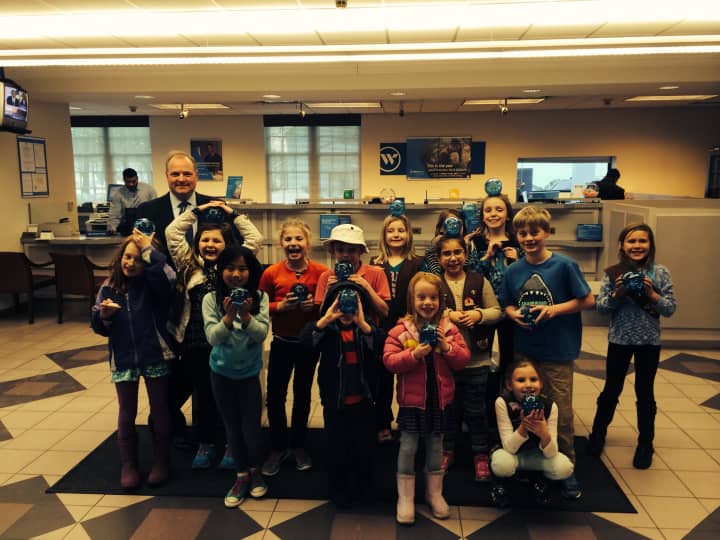 Third-graders from Ox Ridge Brownie Troop 50265 learn about saving their pennies from Webster Bank Vice President Peter Olson during a recent tour.