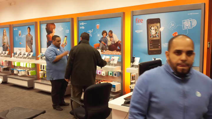 Technician Joshua Rodriguez, left, helps an AT&amp;T customer as Oscar Cohn, tells the Daily Voice about its latest promotion.