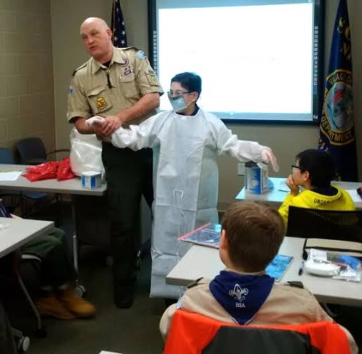 Scarsdale Sgt. Michael Siciliano suits up a Boy Scout in personal protective equipment during the first- aid workshop held at the Scarsdale Police Department.