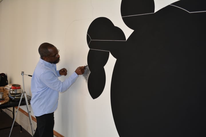 Artist Osi Audu setting up his installation at Crossing Borders exhibit.