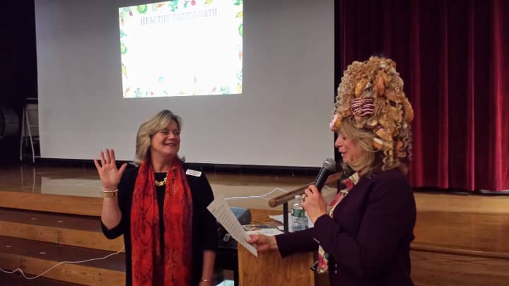 Ellen Lynch, left, president of the Food Bank for Westchester, takes an &quot;eat healthy&quot; oath from Joy Feldman, children&#x27;s author wearing a doughnut hat.